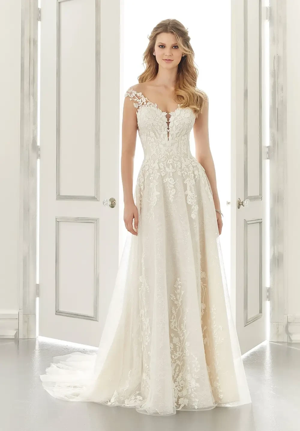 A woman in a beautiful lace wedding dress standing in front of double doors.