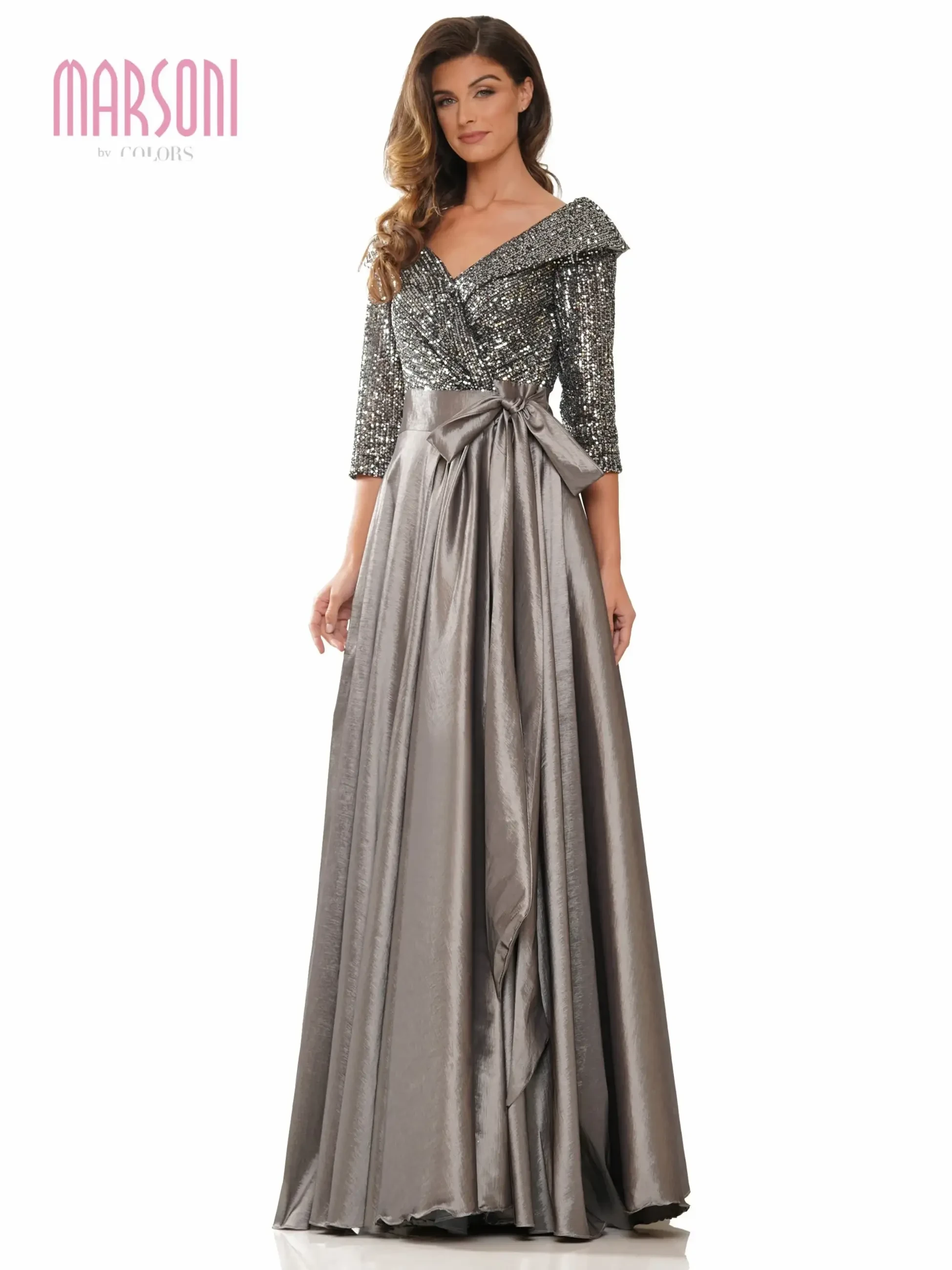 A woman wearing a glamorous, sparkly gray gown with an off-the-shoulder neckline and a long skirt.